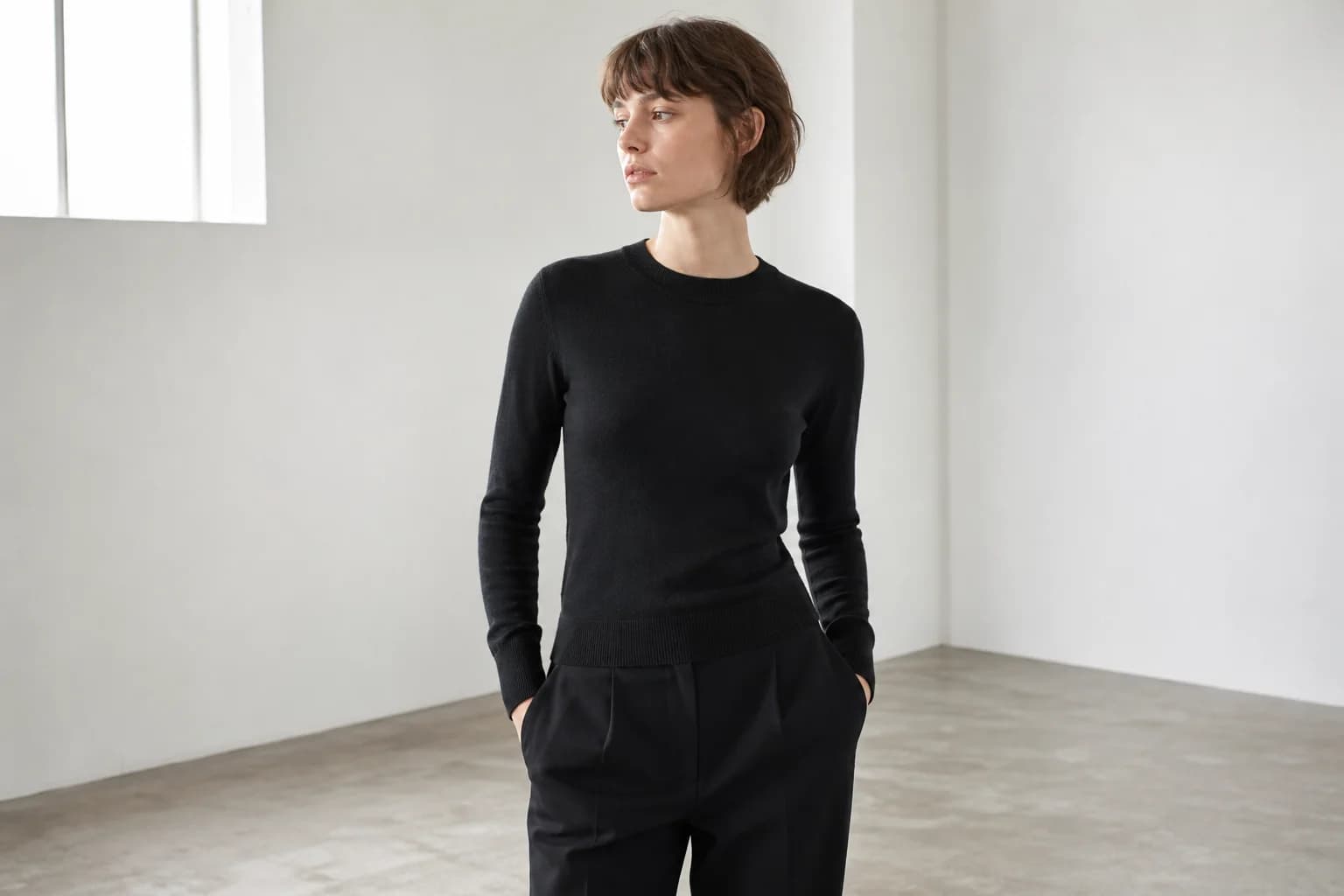 A woman in a black fine-knit sweater in a white gallery room